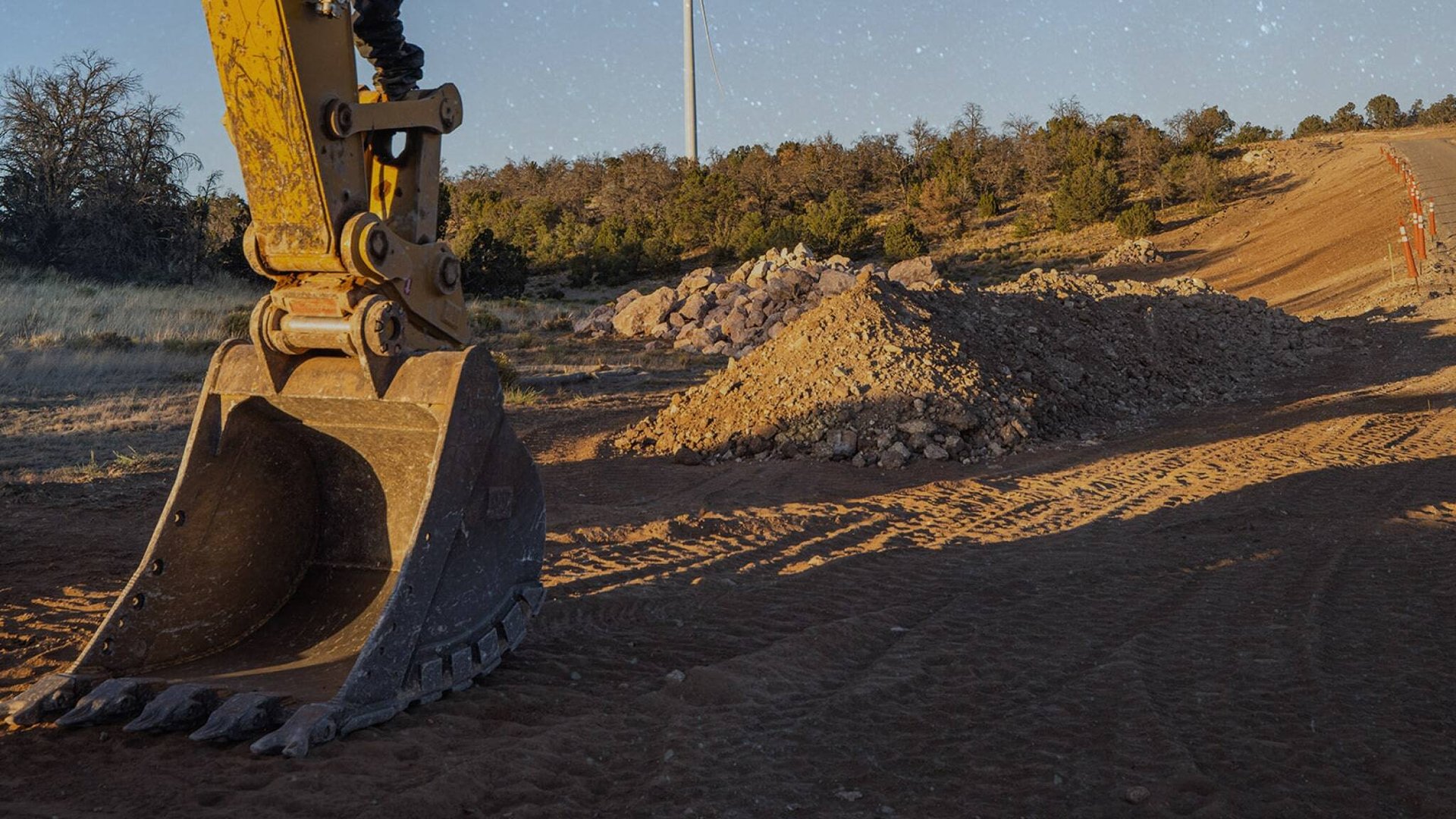 image of excavator bucket resting on the ground during a break at a wind project-min