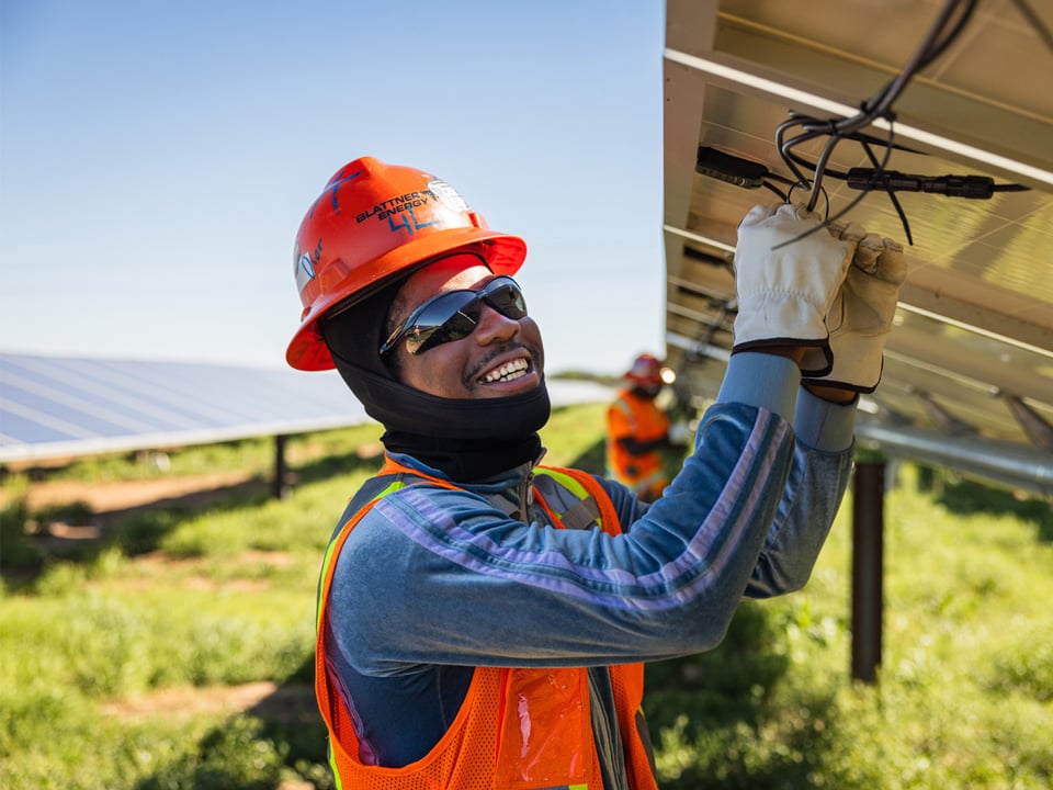 Close up of African American male solar employee working on electrical components of a solar panel on a solar farm