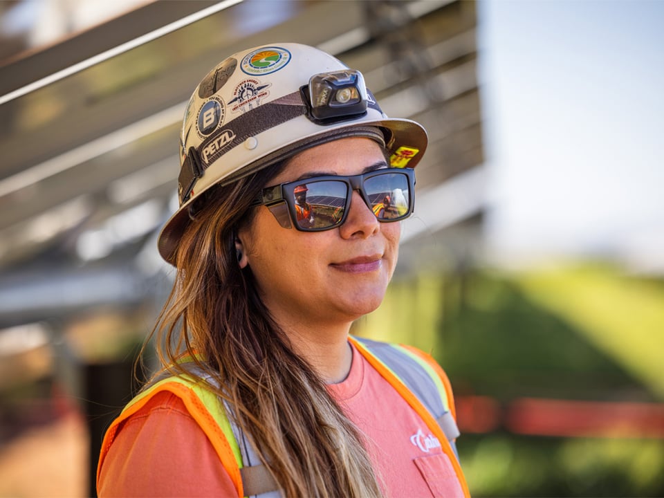 Close up of smiling female employee in the shade of a solar array