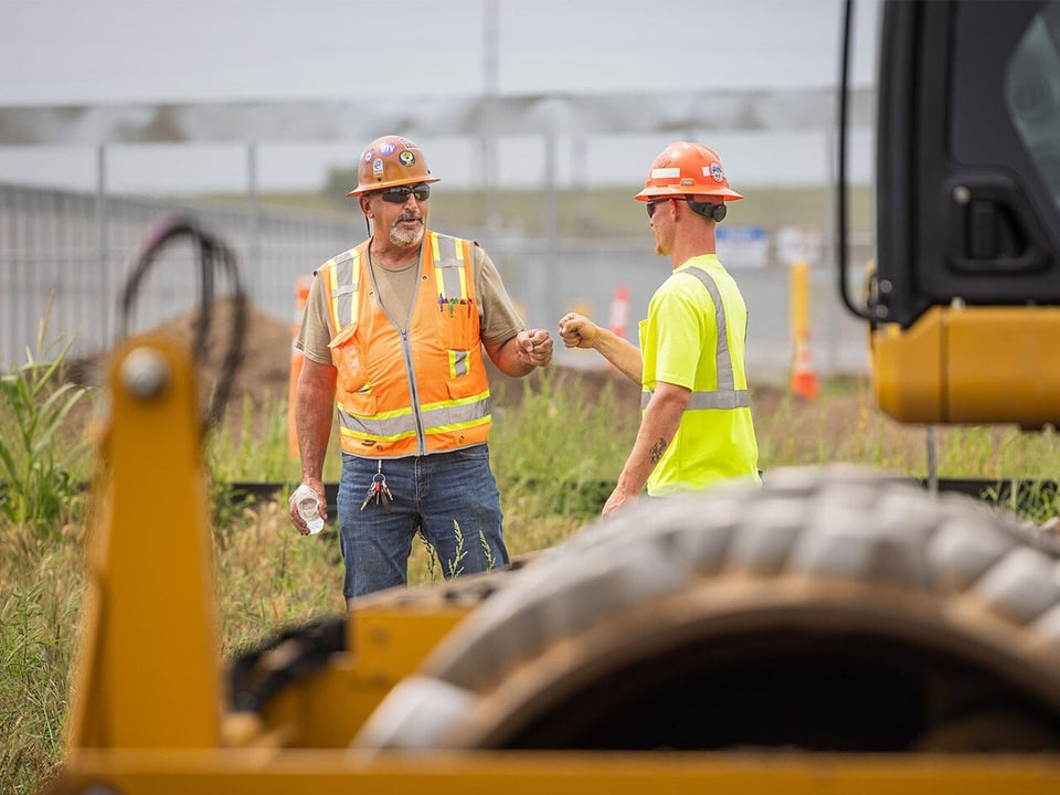 Two male employees fist bump on project site