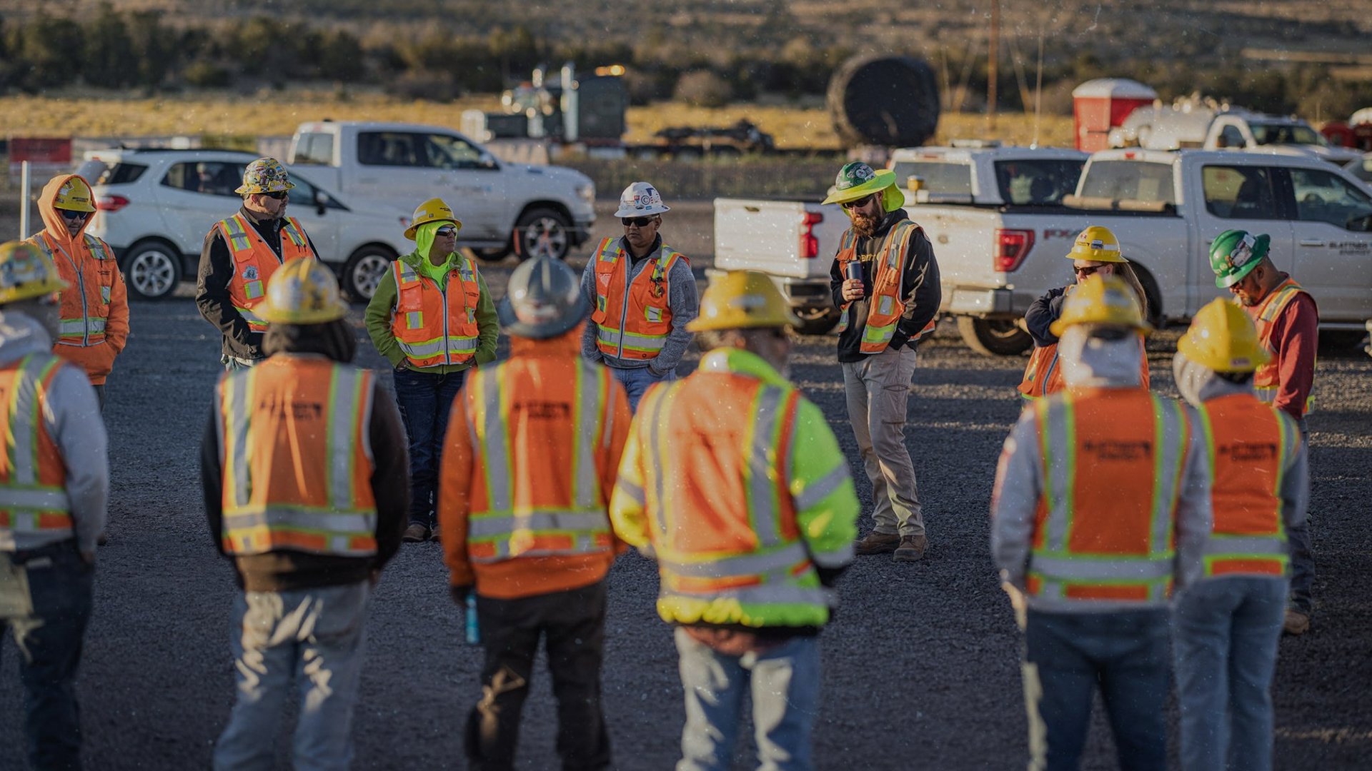 Header-2048x1152 - team of construction workers outside at a renewable energy construction site standing in a circle at an early morning all hands meeting