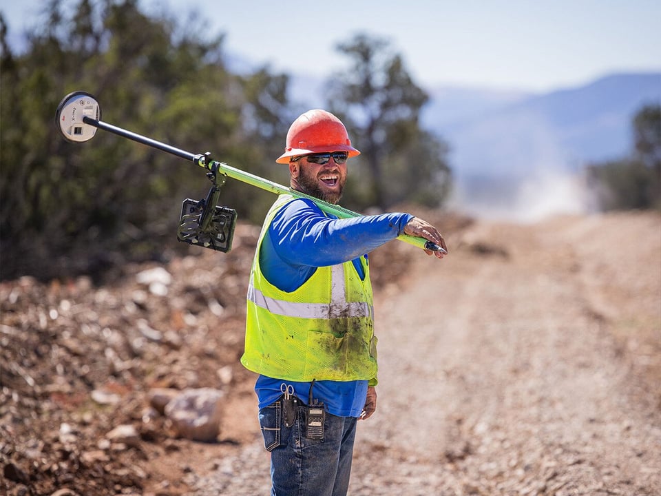 Man smiling with equipment in hand walking down dirt road