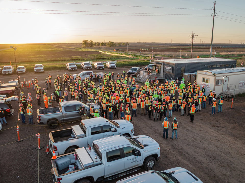 Overhead drone shot of all hands meeting of workers on a project at sunrise