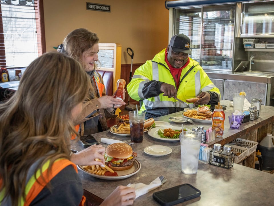 Three workers on their lunch break laughing and eating at a cafe