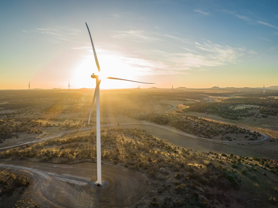 Wind turbine in field with sunset in background