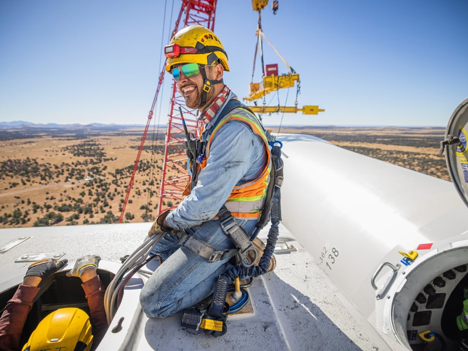 Worker sits atop a wind turbine under construction