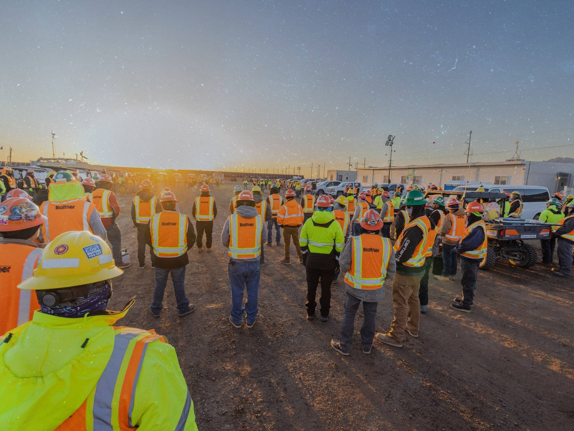 team of solar workers at a sunrise all hands meeting at the laydown yard