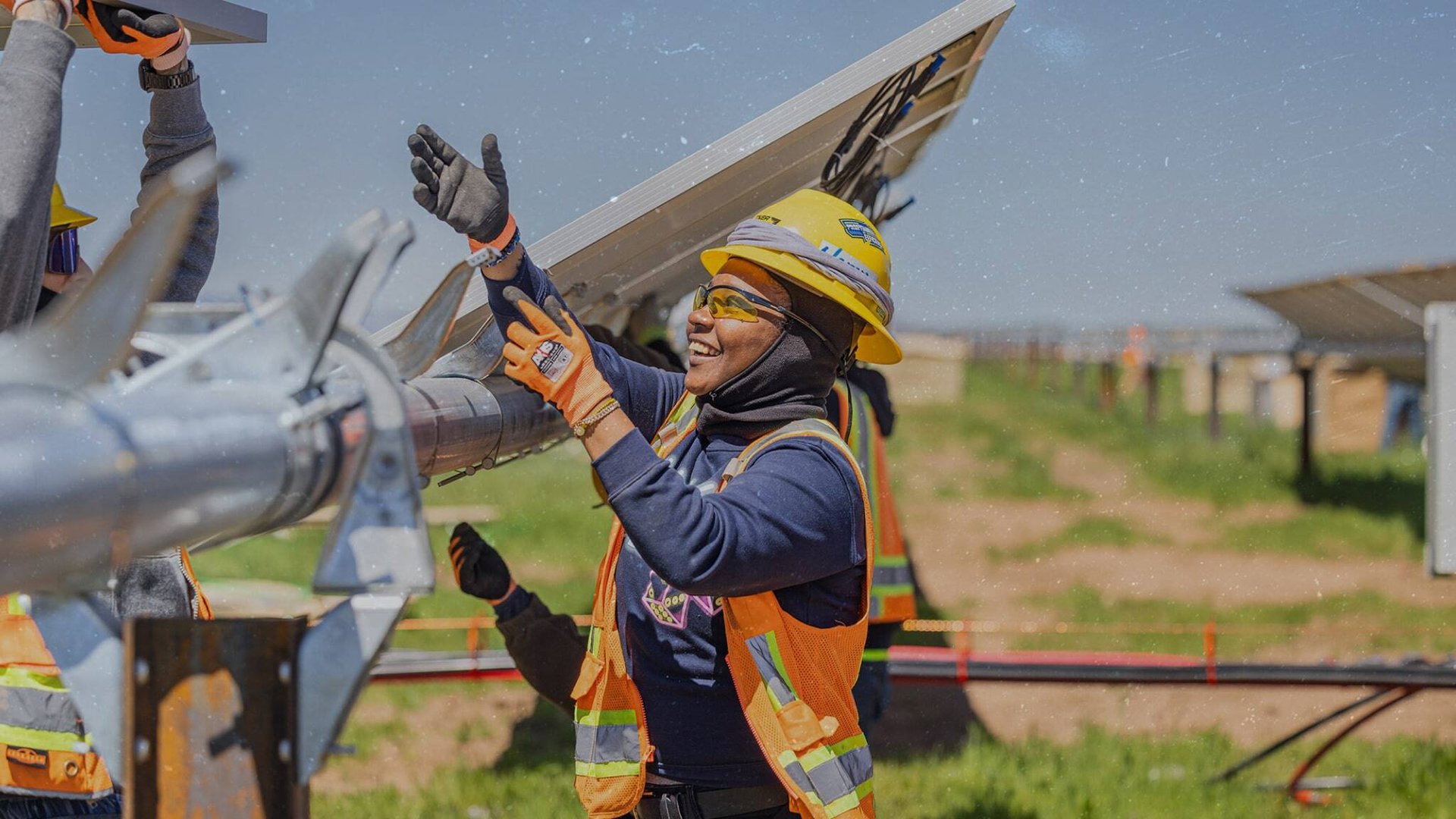 Smiling female African American solar worker reaching for a solar panel to install